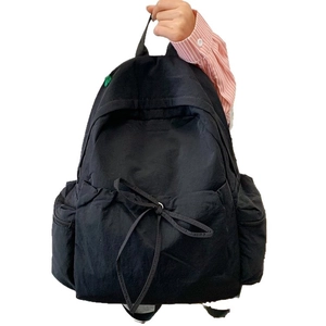 Minimalist black backpack with side pockets and decorative bow for school and travel