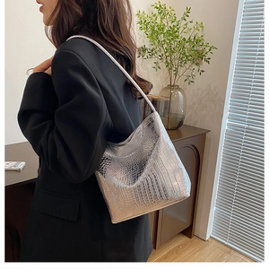 Detail view of silver crocodile embossed leather bucket bag with slim shoulder strap