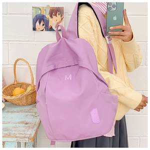 Close-up of a purple school backpack with an M letter print on a textured nylon surface