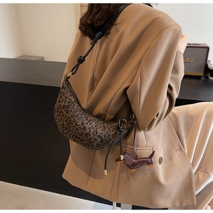 Detail of leopard print croissant bag with knotted leather strap and dog charm