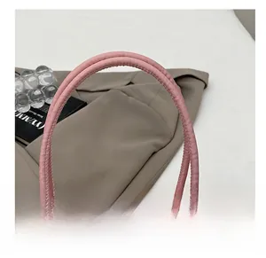 Close-up of the reinforced comfortable handle and stitching on this pink nylon handbag