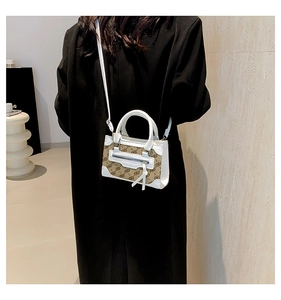 Detail view of stylish monogram canvas mini bag worn over a black coat with leather strap