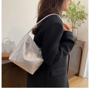Close-up showing the silver crocodile texture and metallic finish of the bucket bag