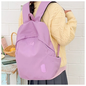 Detailed view of lightweight purple nylon backpack featuring letter embroidery on the front