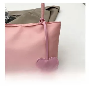 Detail of pink tote bag showing the textured fabric and cute heart leather pendant charm