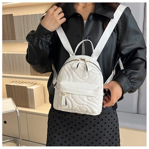 Close-up of white mini quilted backpack with wavy stitching and adjustable straps