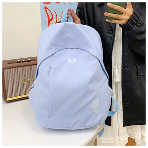 Detailed side view of light blue school backpack with M embroidery and sturdy straps
