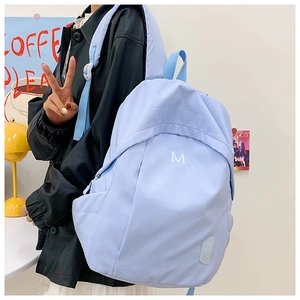 Detail shot of light blue canvas backpack with white embroidered letter M for students