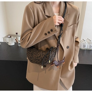 Close-up of leopard print crescent bag with leather dachshund charm on a casual shoulder strap