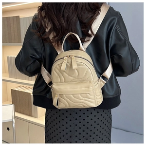 Detail of beige quilted mini backpack showing the wave-pattern texture and compact size