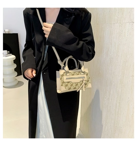 Detail of a chic beige crossbody bag with logo print shown on a model in a black coat