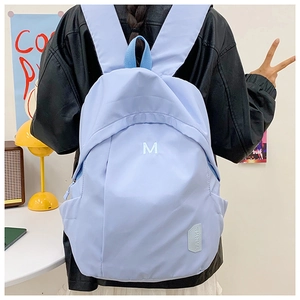 Close-up of a light blue waterproof nylon backpack with white 'M' letter embroidery