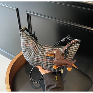 Detail of checkered crescent bag with black leather strap and dog charm pendant