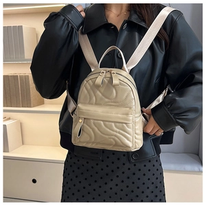 Detail of wave quilted beige mini backpack showing gold zipper and soft PU leather texture
