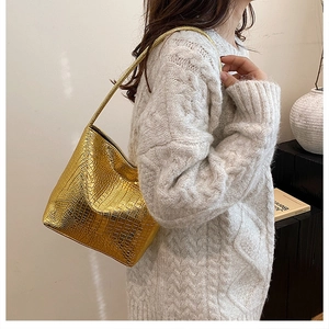 Detail view of gold crocodile embossed shoulder bag with metallic texture and sleek strap
