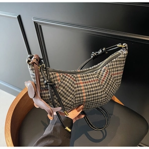 Detail of grey houndstooth crescent bag with orange plaid and dog charm accent