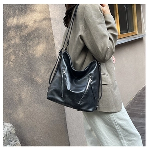 Détail du sac cabas en cuir noir avec double fermeture éclair et texture douce en cuir