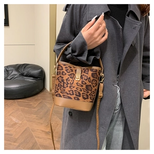 Detail view of leopard print bucket bag with brown leather base and adjustable strap