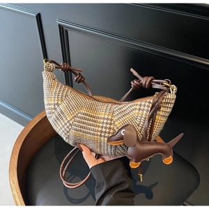 Detail of tweed crescent bag with houndstooth pattern and leather dachshund charm