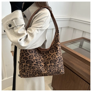 Detail view of leopard print suede hobo bag worn by model in a minimalist room