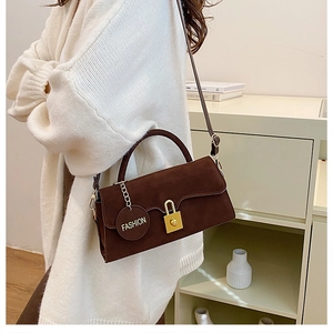 Vue détaillée du sac à main en daim marron foncé avec boucle dorée et pendentif