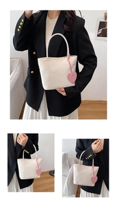 Detail of minimalist beige nylon tote bag with pink heart pendant shown on model