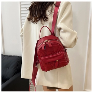 Model wearing red quilted mini backpack with golden zippers and adjustable straps