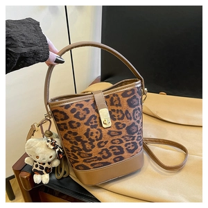 Detail view of leopard print bucket bag with golden lock and cute plush cat charm accessory