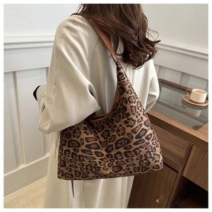 Leopard print suede hobo bag shown with a long beige trench coat in a minimalist setting