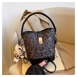 Detail of grey leopard print bucket bag with black leather handle and plush bear charm