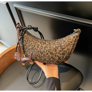 Detail of leopard print croissant bag with knotted strap and small puppy leather charm