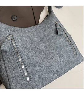 Detail shot of grey matte tote bag with dual decorative metal zippers and grain texture