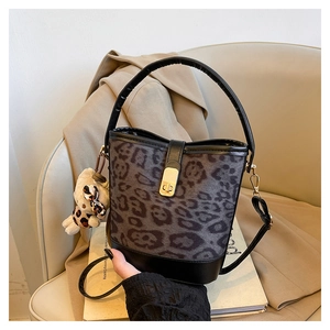 Detail of leopard print bucket bag with gold clasp and plush bear charm on books