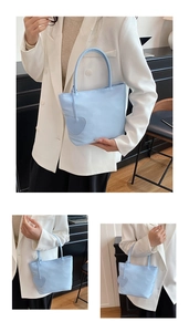 Detail view of mini light blue nylon tote bag with heart charm and slim round handles