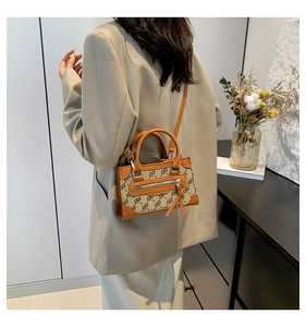 Close-up of beige monogram jacquard bag with brown leather trim and metal zipper detail
