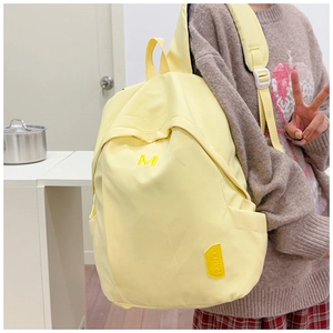 Side view of a light yellow nylon backpack showing side pocket and durable fabric texture