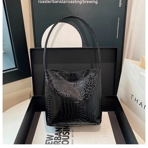 Close-up of black crocodile pattern leather bucket bag inside a premium gift box