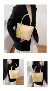 Close-up of beige nylon tote bag with a yellow heart charm showing texture and design