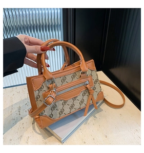 Detail of retro monogram handbag with leather trim and decorative tassel charms