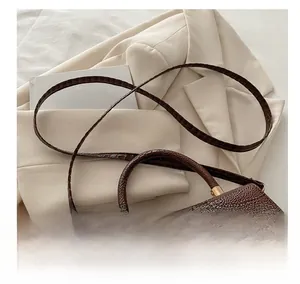 Detail of dark brown crocodile embossed leather handbag with elegant gold metal buckle