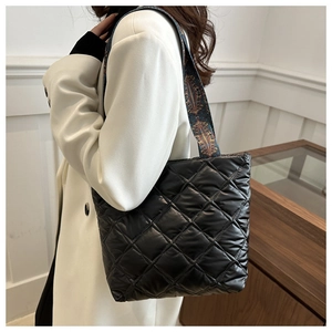 Détail du sac fourre-tout noir matelassé avec bandoulière jacquard et texture losange