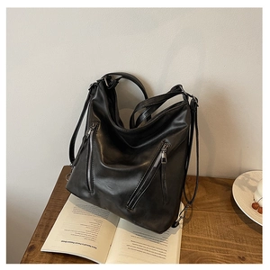Détail d'un sac à dos en cuir noir avec deux fermetures éclair argentées de style hobo