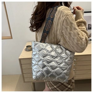 Détail du sac cabas matelassé argenté avec une bandoulière brodée au style vintage