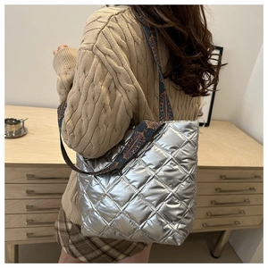 Sac fourre-tout argenté matelassé avec une bandoulière ethnique colorée sur un mannequin