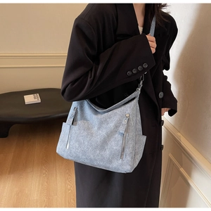 Modern light blue canvas tote bag worn by model featuring side pockets and zippers