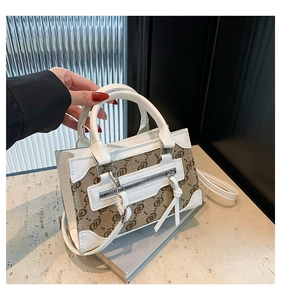 Detail view of stylish white leather and brown monogram canvas crossbody handbag texture