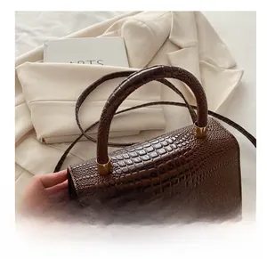 Detailed view of dark brown crocodile embossed leather handbag with golden hardware