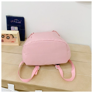 Detail view of pink backpack base and adjustable shoulder straps on a wooden bench