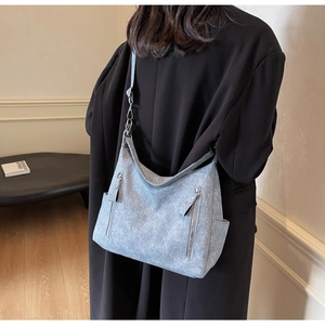 Detail of light blue matte textured tote bag showing side pocket and metal zippers