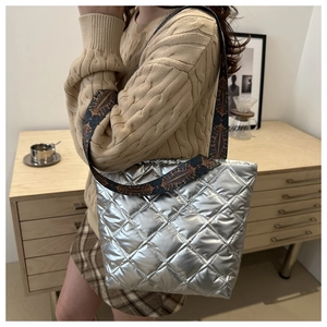 Détail du sac cabas argenté matelassé avec une large bandoulière au motif ethnique